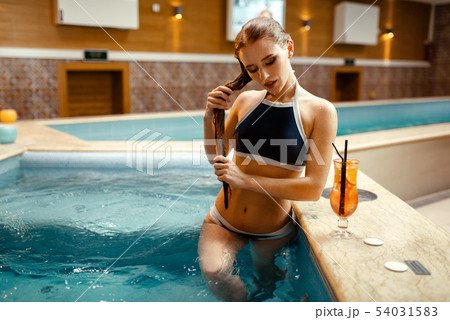Woman with fruit cocktail at the pool side indoors 54031583