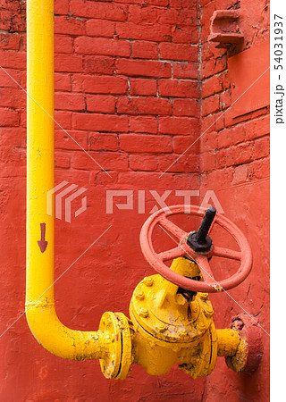 yellow pipeline with valve against the red wall yellow pipeline with valve against the red wall 54031937
