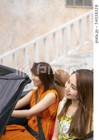 おしゃれな街でオープンカーに乗り気持のいいそよ風で気分も上がる女子旅中の可愛い女性二人 54038328