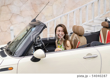 初めてのデートで彼氏のオープンカーの助手席に乗り恥ずかしそうな表情をする可愛い美人女性 54040287
