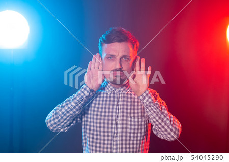Portrait of a young handsome man with a beard and a plaid shirt showing his ears posing against a 54045290