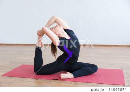 Young girl doing yoga. Performs stretching of the 54045874