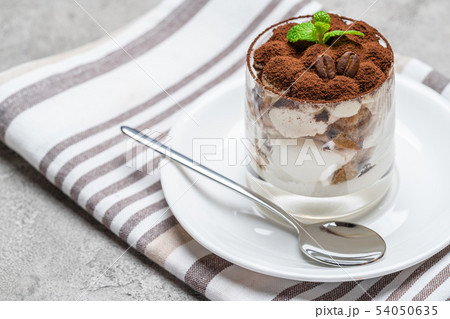 Classic tiramisu dessert in a glass on concrete background Classic tiramisu dessert in a glass on concrete background 54050635