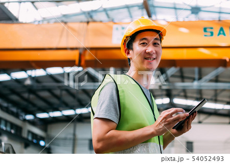 Young Asian male factory worker holding a digital tablet Young Asian male factory worker holding a digital tablet 54052493