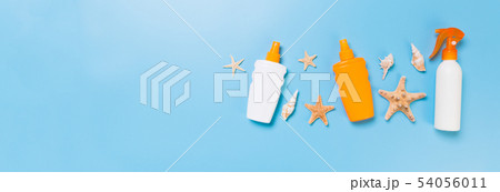 Sunscreen bottles with seashells on blue table top Sunscreen bottles with seashells on blue table top 54056011