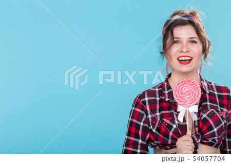 Diet, dessert and junk food - woman pin-up style with lollipop over the blue background copy space. 54057704