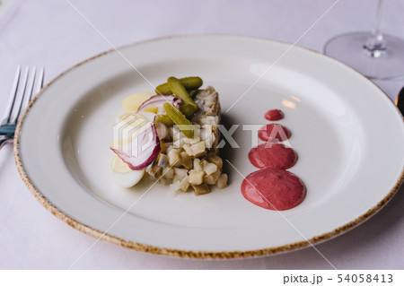 Restaurant delicacy dish on a purple tablecloth. White plate with herring Restaurant delicacy dish on a purple tablecloth. White plate with herring 54058413