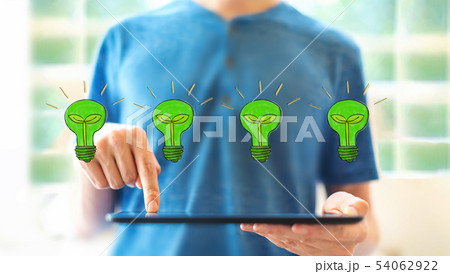 Eco light bulbs with man using a tablet 54062922