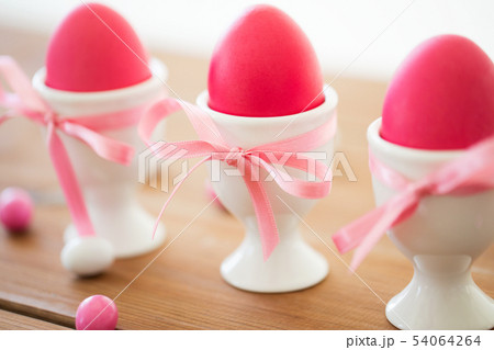 easter eggs in holders and candy drops on table 54064264