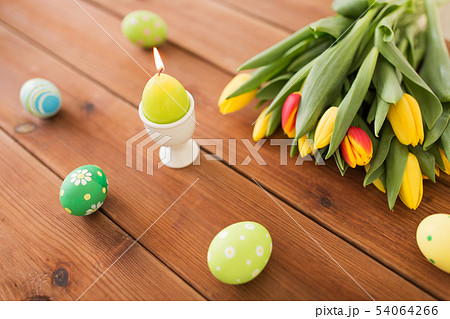 candle in shape of easter egg and tulip flowers 54064266