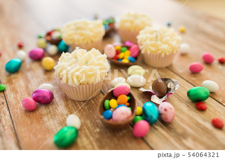cupcakes with chocolate eggs and candies on table 54064321
