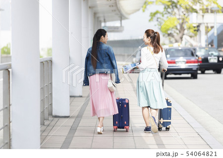 キャリーケースを引いて歩く女性2人 54064821