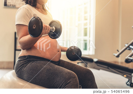 Active pregnant woman exercise in fitness center. Active pregnant woman exercise in fitness center. 54065496