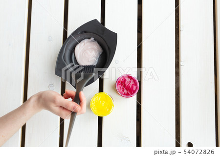Color and hairdresser concept - female hairdresser in process of mixing hair dye color on the table Color and hairdresser concept - female hairdresser in process of mixing hair dye color on the table 54072826