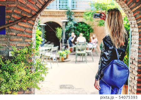 A girl with blond hair takes pictures of the A girl with blond hair takes pictures of the 54075393