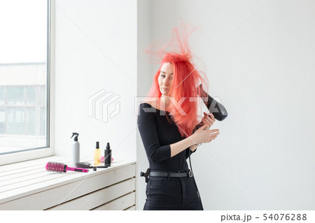 Hairdresser, style, people concept - woman is blowing dry her colored hair 54076288