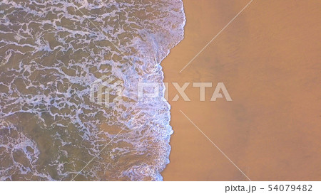 Aerial view of beach with waves rolling into the Aerial view of beach with waves rolling into the 54079482