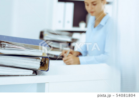 Binders with papers are waiting to be processed by business woman or bookkeeper back in blur 54081804