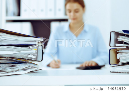 Binders with papers are waiting to be processed by business woman or bookkeeper back in blur 54081950