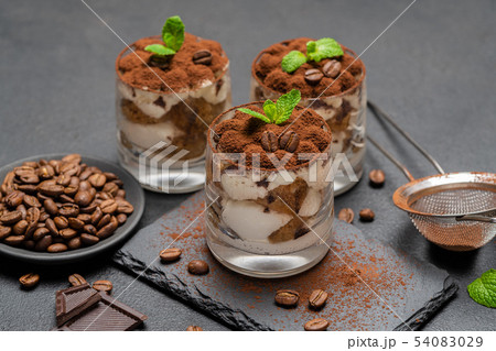 Classic tiramisu dessert in a glass on stone serving board on dark concrete background Classic tiramisu dessert in a glass on stone serving board on dark concrete background 54083029