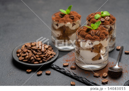 Classic tiramisu dessert in a glass on stone serving board on dark concrete background 54083055