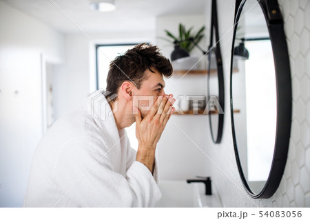 Young man washing face in the bathroom in the morning, daily routine. Young man washing face in the bathroom in the morning, daily routine. 54083056