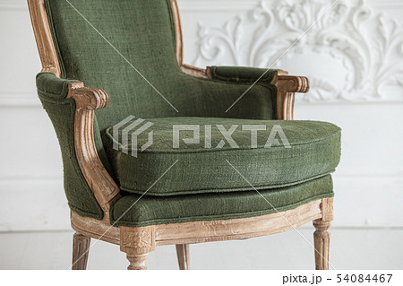 Vintage green armchair against the wall with plaster stucco patterns. Selective focus. Close up. Vintage green armchair against the wall with plaster stucco patterns. Selective focus. Close up. 54084467