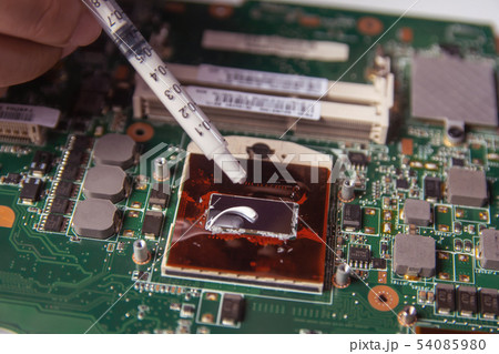 Technician applying thermal paste with syringe on Technician applying thermal paste with syringe on 54085980