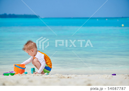 Three year old toddler playing on beach Three year old toddler playing on beach 54087787