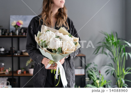 White peonies in womans hands. Beautiful fresh peony flower for catalog or online store. Floral shop 54088960