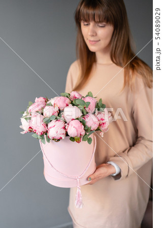 Pink peonies in pink round box. Beautiful peony flower in womans hands for catalog or online store 54089029
