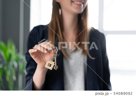 Young pretty woman smiles. House key in womans hands. . Modern light lobby interior. Real estate 54089092