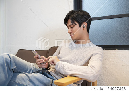ワイヤレスヘッドホンをしてスマホを操作する男性 ワイヤレスヘッドホンをしてスマホを操作する男性 54097868