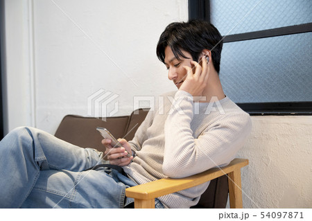 ワイヤレスヘッドホンをしてスマホを操作する男性 ワイヤレスヘッドホンをしてスマホを操作する男性 54097871