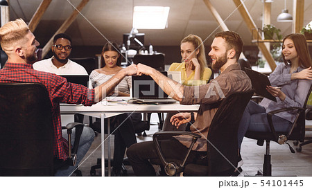 Fist bump. Colleagues celebrating successful teamwork in office Fist bump. Colleagues celebrating successful teamwork in office 54101445
