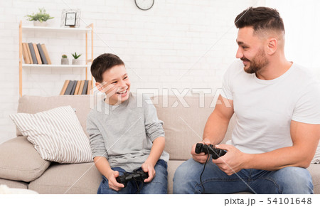 Cheerful father and son playing video game at home Cheerful father and son playing video game at home 54101648