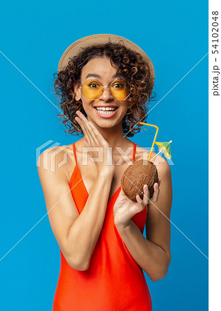 Excited black girl in swimwear holding tropical cocktail in coconut shell Excited black girl in swimwear holding tropical cocktail in coconut shell 54102048