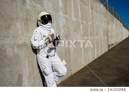 Futuristic astronaut in a helmet against gray walls. Fantastic Cosmic Costume. 54103088