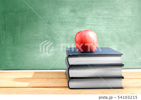 Pile of books with apple on the wooden table 54103215