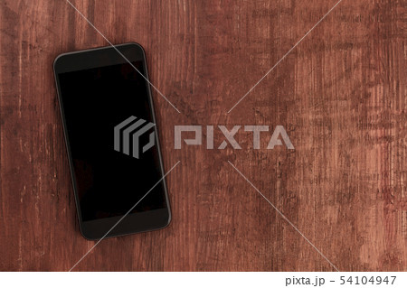 A smartphone, shot from the top on a dark wooden background, a mockup of a blank screen with copy 54104947