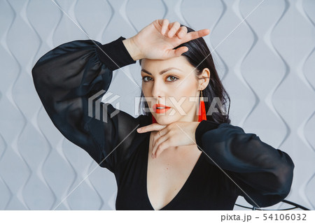 Fashion portrait of a stylish brunette girl wearing a black dress. Woman with long hair wearing red Fashion portrait of a stylish brunette girl wearing a black dress. Woman with long hair wearing red 54106032