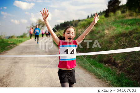 Small girl runner crossing finish line in a race competition in nature. Small girl runner crossing finish line in a race competition in nature. 54107003