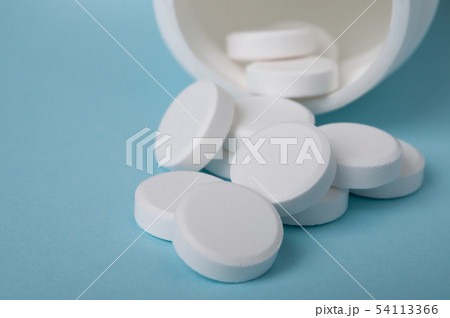 closed up white pills spilling oyt of the bottle 54113366