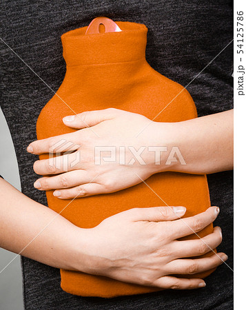 Girl having stomach ache, holding hot water bottle Girl having stomach ache, holding hot water bottle 54125786