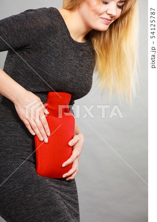 Girl having stomach ache, holding hot water bottle Girl having stomach ache, holding hot water bottle 54125787