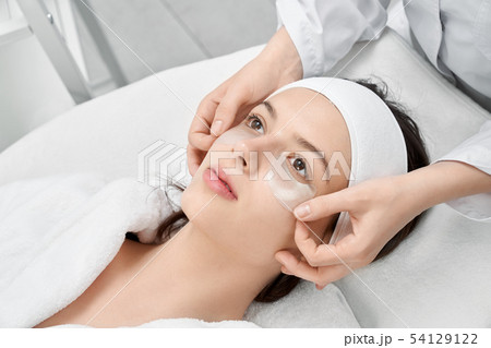 Brunette lying with patches under eyes in spa salon 54129122