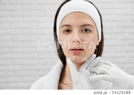 Attractive client posing while cosmetologist doing injection Attractive client posing while cosmetologist doing injection 54129188
