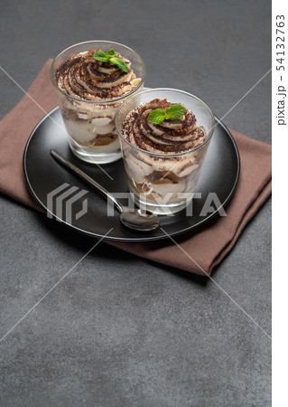 Classic tiramisu dessert in a glass on dark concrete background Classic tiramisu dessert in a glass on dark concrete background 54132763