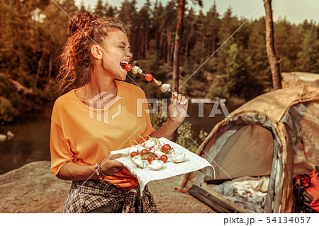 Delighted happy woman trying a tasty tomato 54134057