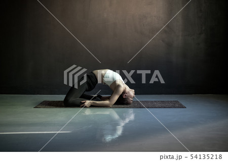 Woman practicing yoga, doing Pigeon exercise, Kapotasana pose. 54135218